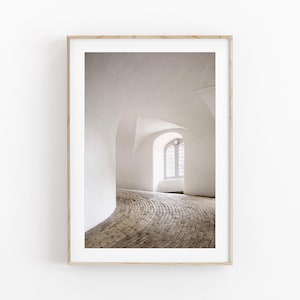 Puede incluir: Impresión enmarcada de un pasillo abovedado blanco con suelo de ladrillo. El pasillo se curva hacia una ventana con un patrón de rejilla. Las paredes y el techo son blancos, creando un ambiente luminoso y espacioso.