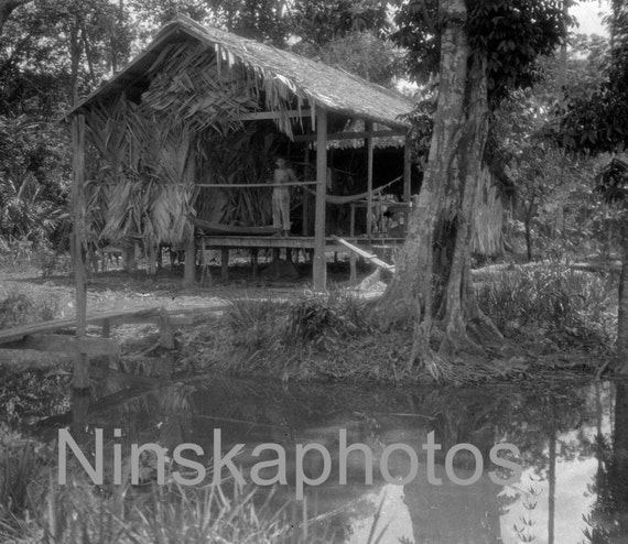 A boy in a boatshed alongside the Amazon, North Brazil by J. Dearden Holmes, 1920s antique photo reprint, vintage boat, paddle boat
