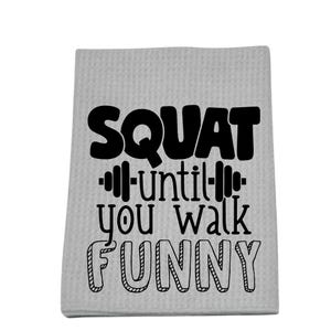 May include: A light gray, textured towel with the phrase "SQUAT until you walk FUNNY" in black lettering. The word "SQUAT" is in a bold font, and the word "FUNNY" is outlined.