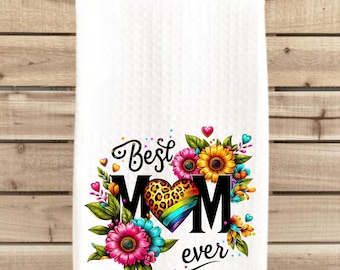 May include: White kitchen towel featuring a colourful floral design and the text "Best Mom Ever". The floral design includes a heart with a leopard print and rainbow stripes.