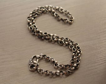 May include: A silver chain necklace with a detailed clasp. The chain is made of small, linked circles.