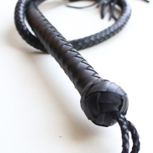 May include: A black leather bullwhip with a braided handle and a long, braided tail.