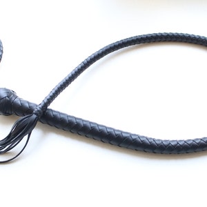 May include: A black leather bullwhip with a braided handle and a tassel.