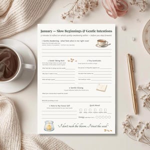 May include: A journal page titled "January - Slow Beginnings & Gentle Intentions" with prompts for reflection. A cup of coffee, a pen, and a candle are arranged around the journal. The journal has a quote at the bottom.