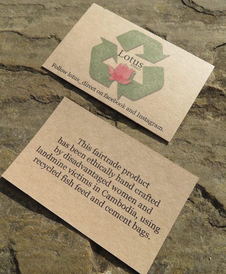 May include: A brown paper business card with a green recycling symbol and the text "Lotus Direct" and "Follow lotus_direct on facebook and Instagram." The card also includes the text "This fairtrade product has been ethically hand crafted by disadvantaged women and landmine victims in Cambodia, using recycled fish feed and cement bags."