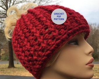 Peut inclure: Chapeau en crochet rouge avec un trou au sommet pour une queue de cheval. Le chapeau est sur une tête de mannequin. Le texte "CROCHET PDF PATTERN" est sur un cercle blanc.