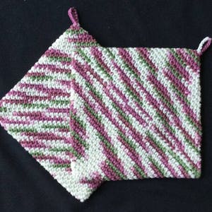May include: Two crocheted pot holders in a pink, white, and green striped pattern. The pot holders have a loop at the top for hanging.
