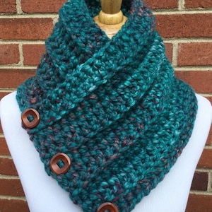 May include: Teal and purple crocheted cowl with wooden buttons. The cowl is folded over and has a relaxed, slouchy fit.
