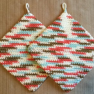 May include: Two crocheted pot holders in a striped pattern of brown, white, pink, and blue.