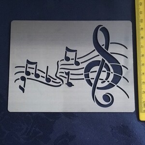 May include: A metal stencil with a treble clef and musical notes. The stencil is designed for crafting and decorating projects.