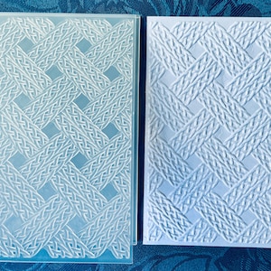 Pode incluir: Duas pastas de relevo retangulares transparentes e brancas com um padrão de tecido de cesta. Estas pastas são usadas para artesanato e projetos de papel. São feitas de plástico.