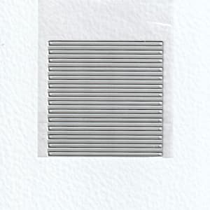 Op de afbeelding: Een rechthoekig, zilverkleurig metalen object met talrijke parallelle, horizontale lijnen. De lijnen zijn gelijkmatig verdeeld en creëren een textuur. Het object bevindt zich tegen een witte achtergrond, mogelijk in een transparante plastic hoes.