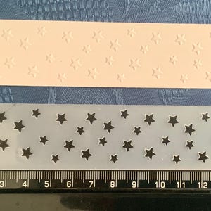 May include: Two clear plastic sheets with a star pattern. The top sheet has a raised star pattern and the bottom sheet has a cut-out star pattern.