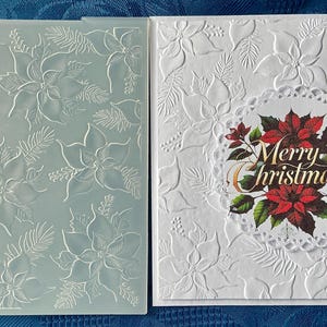 May include: A translucent plastic embossing folder featuring a raised poinsettia and pine needle pattern next to a white square greeting card with the same embossed design and a central circular die-cut topper with red poinsettias and Merry Christmas text.