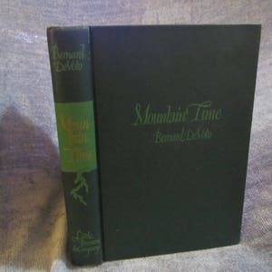 May include: A green hardcover book titled "Mountain Time" by Bernard DeVoto. The book has a spine with the title "Mountain Time" and the author's name.