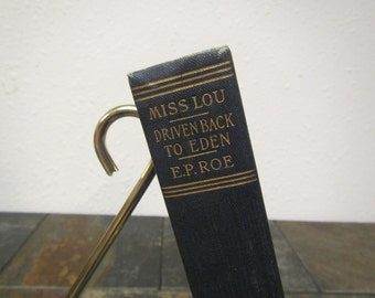 May include: A black book with gold lettering on the spine. The title is "Miss Lou Driven Back to Eden" by E.P. Roe.
