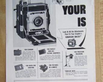 Może przedstawiać: Czarno-srebrny aparat fotograficzny Graflex z różnymi akcesoriami, w tym uchwytem na rolkę, uchwytem na arkusze, tylnym panelem Polaroid i powiększalnikiem. Tekst "Your is" jest wyświetlany dużymi literami nad aparatem. Tekst "Graflex Price-Winning Camera" jest wyświetlany na dole obrazu.