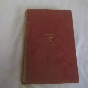 May include: A red hardcover book with a gold embossed design of a running figure on the front cover.