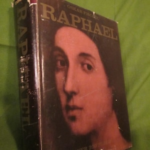 May include: A brown hardcover book with the title "Raphael" in gold lettering. The book cover features a close-up portrait of a person with brown hair and a light brown complexion. The text "OSKAR FISCHEL" is printed in gold lettering above the title. The text "OVER 300" is printed in gold lettering at the bottom of the cover.