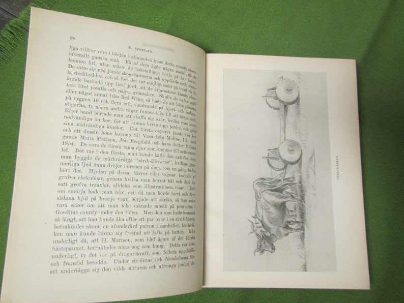 May include: A black and white illustration of a wooden cart pulled by two oxen. The cart has two large wooden wheels and a simple wooden frame. The oxen are depicted in a realistic style, with detailed musculature and horns.
