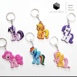 May include: A collection of six colorful pony-shaped keychains. Each keychain features a different pony design with vibrant colors, attached to a silver metal keyring. The keychains are from JAC BOUTIQUE.