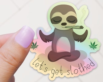 May include: A sticker featuring a cartoon sloth meditating with a joint in its mouth. The sloth is surrounded by a rainbow cloud and the text "let's get slothed" is below it.