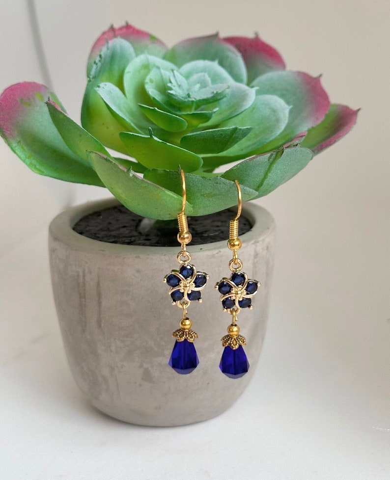 These gorgeous sapphire crystal flower teardrop earrings work well with many different fashion styles and makes a great gift for those born under the September birthstone. 

2  inches
Gold ear wires
Rubber security backs