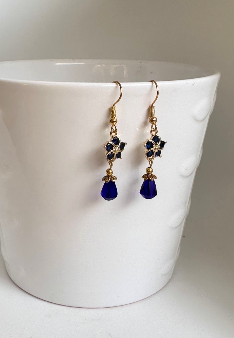 These gorgeous sapphire crystal flower teardrop earrings work well with many different fashion styles and makes a great gift for those born under the September birthstone. 

2  inches
Gold ear wires
Rubber security backs