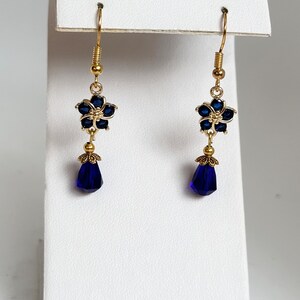 These gorgeous sapphire crystal flower teardrop earrings work well with many different fashion styles and makes a great gift for those born under the September birthstone. 

2  inches
Gold ear wires
Rubber security backs
