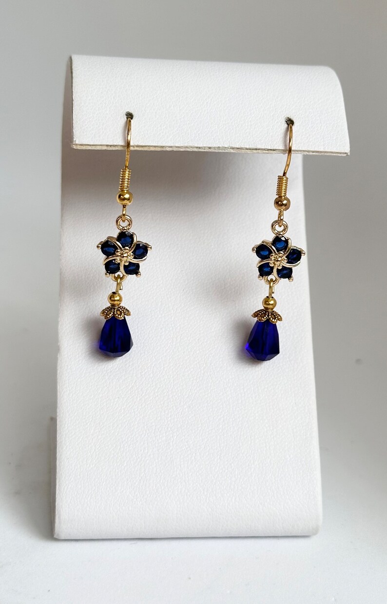 These gorgeous sapphire crystal flower teardrop earrings work well with many different fashion styles and makes a great gift for those born under the September birthstone. 

2  inches
Gold ear wires
Rubber security backs