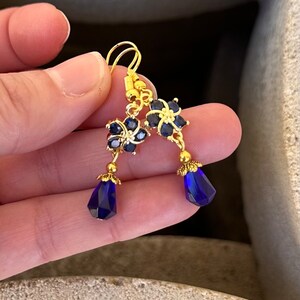 These gorgeous sapphire crystal flower teardrop earrings work well with many different fashion styles and makes a great gift for those born under the September birthstone. 

2  inches
Gold ear wires
Rubber security backs