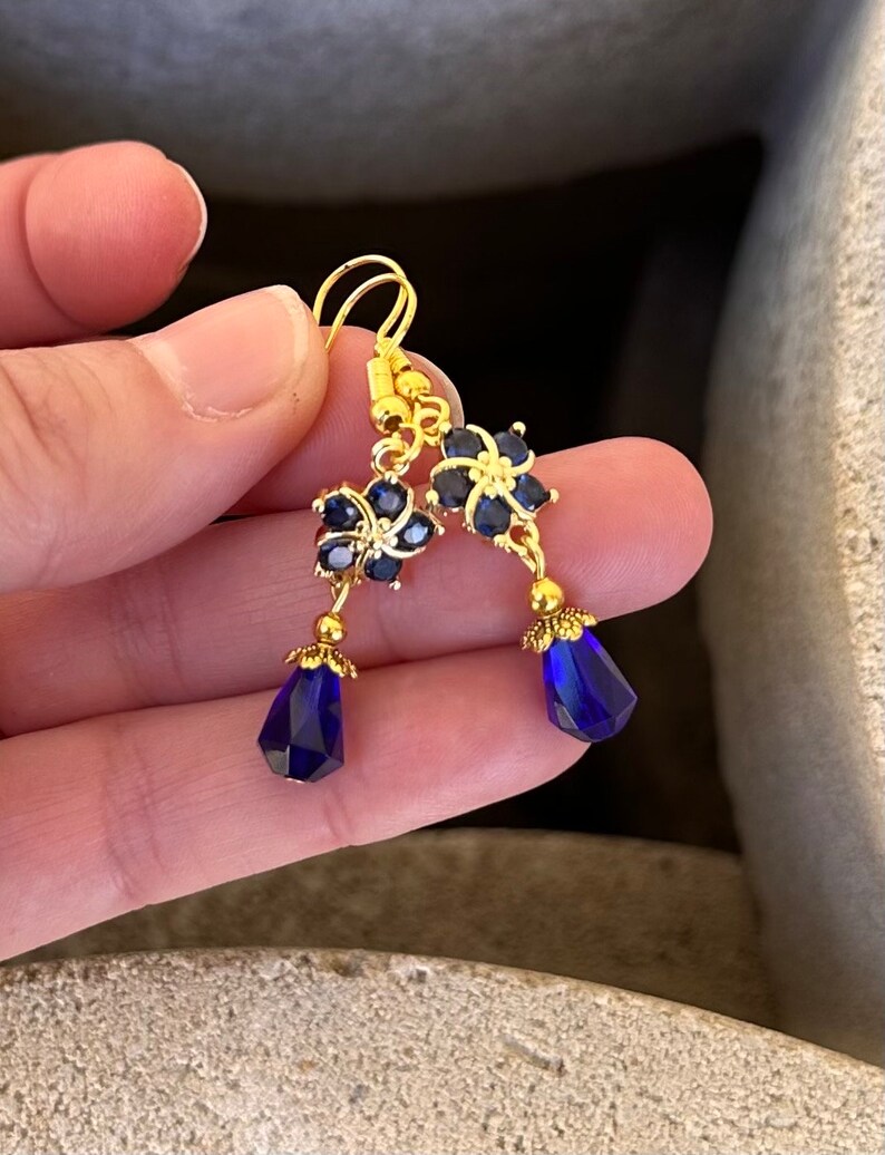 These gorgeous sapphire crystal flower teardrop earrings work well with many different fashion styles and makes a great gift for those born under the September birthstone. 

2  inches
Gold ear wires
Rubber security backs