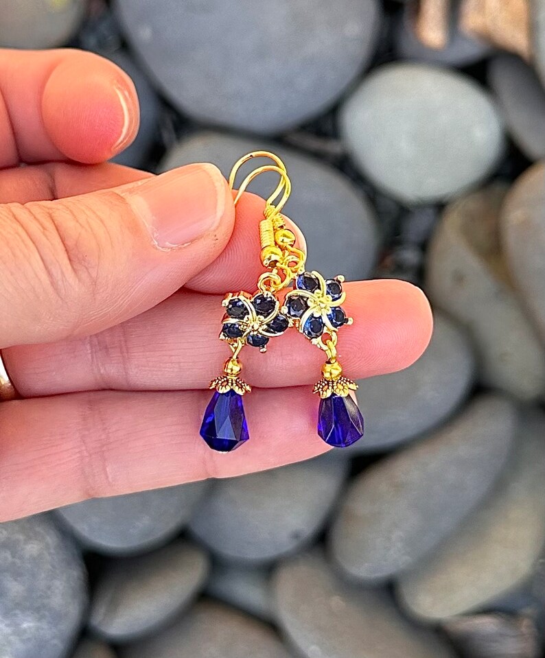 These gorgeous sapphire crystal flower teardrop earrings work well with many different fashion styles and makes a great gift for those born under the September birthstone. 

2  inches
Gold ear wires
Rubber security backs
