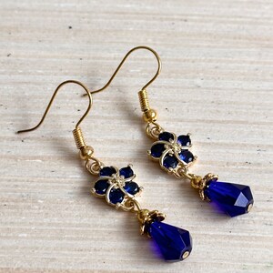 These gorgeous sapphire crystal flower teardrop earrings work well with many different fashion styles and makes a great gift for those born under the September birthstone. 

2  inches
Gold ear wires
Rubber security backs