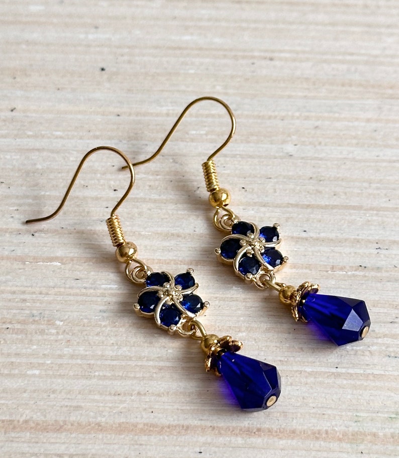 These gorgeous sapphire crystal flower teardrop earrings work well with many different fashion styles and makes a great gift for those born under the September birthstone. 

2  inches
Gold ear wires
Rubber security backs