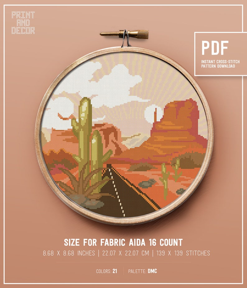 May include: A cross-stitch pattern featuring a desert landscape with a road, cacti, and a mountain in the background. The pattern is framed in a wooden hoop and is labeled "PDF Instant Cross-Stitch Pattern Download". The size of the pattern is 8.68 x 8.68 inches, 22.07 x 22.07 cm, and 139 x 139 stitches. The pattern uses 21 colors and is designed for Aida 16 count fabric.
