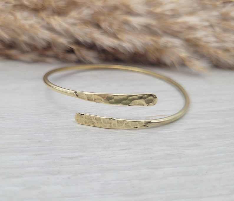 May include: A gold hammered metal bangle bracelet with a simple, open design.