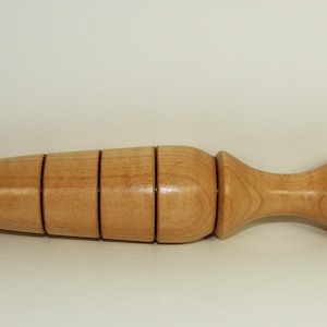 May include: A wooden planting tool with a pointed tip and a rounded handle. The tool has five black bands around the middle section.
