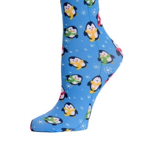 May include: A blue knee-high sock featuring a pattern of cartoon penguins wearing scarves in yellow, green, and red. The penguins are set against a background of white snowflakes.