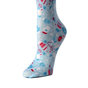 May include: A pair of blue knee-high socks with a winter-themed pattern. The pattern features red and white mittens, snowflakes, and hats.