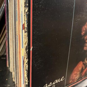 May include: Close-up of the spine of a vinyl record with a red and white stripe along the edge. The record is titled "Requiem" and is part of a collection of records.