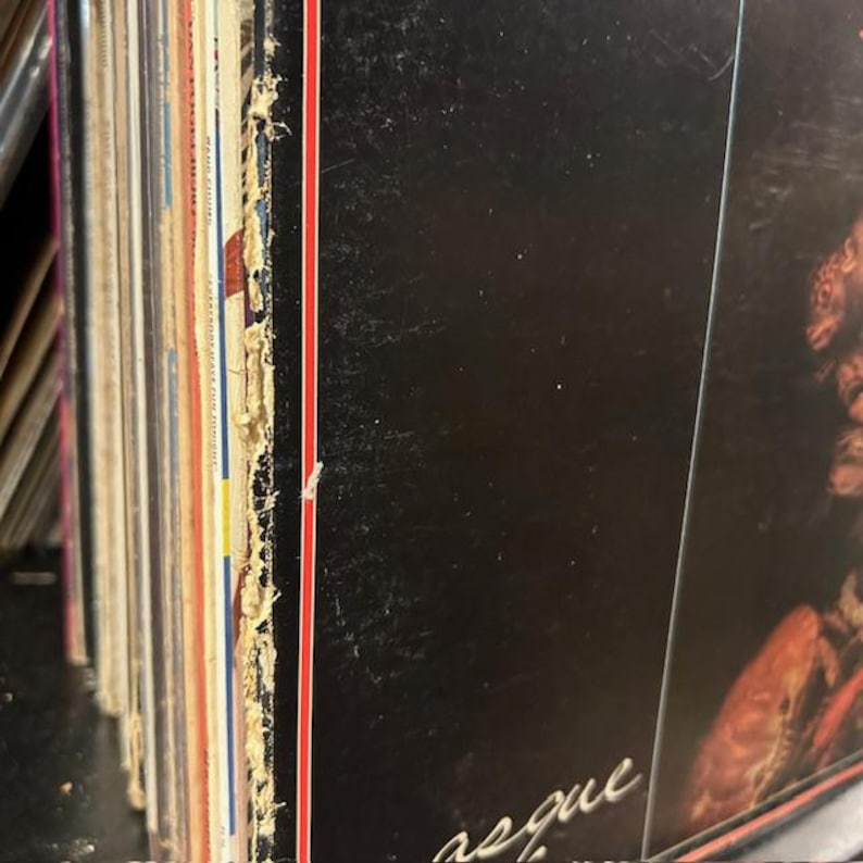 May include: Close-up of the spine of a vinyl record with a red and white stripe along the edge. The record is titled "Requiem" and is part of a collection of records.