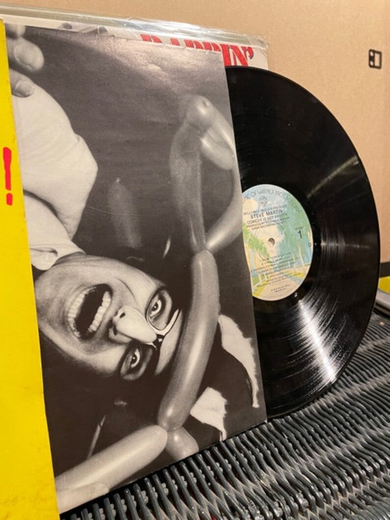 May include: A black vinyl record with a white label featuring a photo of Steve Martin. The album cover features a black and white photo of Steve Martin with a surprised expression, surrounded by balloons.