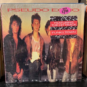May include: A vintage vinyl record album cover featuring three men in leather jackets. The album is titled "Pseudo Echo" and the album cover text reads "Love and Adventure" with the words "Featuring the Hit Track "Funky Town" in a white box on the cover. The album cover is in a sale sticker with the price $7.99.