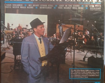 Könnte beinhalten: Ein Schwarzweißfoto von Frank Sinatra, der in einem Aufnahmestudio auftritt. Das Bild zeigt Sinatra, der in ein Mikrofon singt, mit einem großen Orchester hinter ihm. Der Text auf dem Albumcover lautet "The Concert Sinatra" und listet die auf dem Album enthaltenen Songs auf. Das Album ist eine Veröffentlichung von Reprise Records.