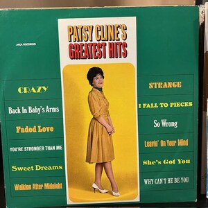 May include: Vintage vinyl record album cover for Patsy Cline's Greatest Hits. The album cover features a photo of Patsy Cline in a mustard-colored dress. Song titles include "Crazy," "Sweet Dreams," and "I Fall to Pieces."