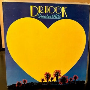 May include: Album cover for Dr. Hook's Greatest Hits. The design features a large yellow heart against a gradient blue and dark blue background. Palm trees with red and orange fronds are silhouetted at the bottom.