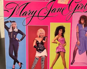 May include: A vintage vinyl record cover titled ONLY FOUR YOU by Mary Jane Girls. The bright pink cover features four rectangular photo insets of performers in 1980s fashion, including a black jumpsuit, a leather top with zebra print boots, a pink dress, and a purple dress.