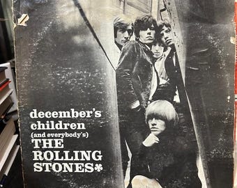 May include: A black and white vinyl record cover for The Rolling Stones album titled December's Children (And Everybody's). The cover features a group portrait of the band members and the London Records logo in the bottom right corner.