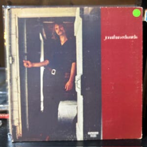 May include: Album cover featuring a man in a dark shirt and pants standing in a doorway. The album's title is "jonathan edwards" in white text on a red background. The cover has a vintage aesthetic.